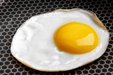 Tava yüzeyindeki sahanda yumurtanın yakın plan fotoğrafı.