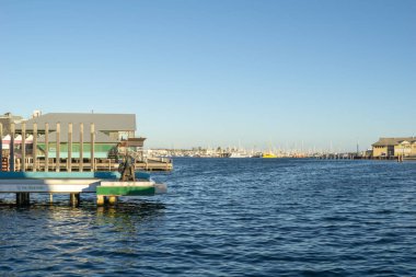 Fremantle, Avustralya - 8 Mayıs 2018; Güneş parlaması ve tuzaklar heykel ve liman waterfront apartmanda batımında bronz balıkçı siluet.