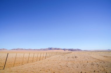 Namibya geniş açık çöl manzara uzak tepeleri ile kırmızı kum sürüklenir ilerliyor uzun çit bölü.