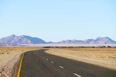 Uzun ve dolambaçlı bir yol Namibya çöl manzarası ile uzak tepelerin üzerinden