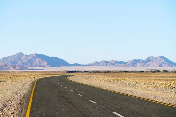 Длинная Извилистая Дорога Через Пустынный Ландшафт Намибии Отдаленными Холмами — Бесплатное стоковое фото