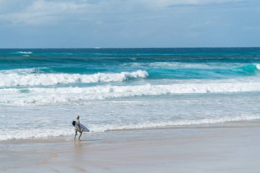 Coolangatta, Avustralya - July10 2018; Geniş surf beach Plajı önünde sörf sörf tahtası taşıyan sörfçü ile