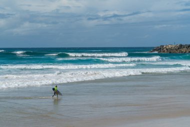 Coolangatta, Avustralya - July10 2018; Geniş surf beach Plajı önünde sörf sörf tahtası taşıyan sörfçü ile