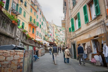 Riomaggiore İtalya - 24 Nisan 2011; Karakteristik Akdeniz pastel renkli çok katlı mağazalar ve daireler arasında dar şerit boyunca geçen insanlar