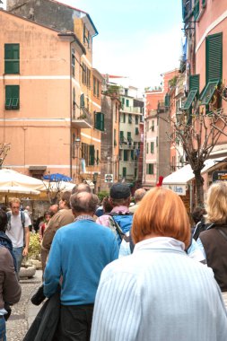 Monterosso İtalya - 24 Nisan 2011; Turistler uzun boylu karakteristik daireler, turistik dükkanlar ve kafeler arasında yürürken dikey kompozisyon küçük Cinque Terre şehirde cadde kalabalık.