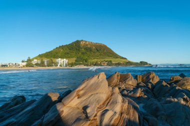 Landmark Mount Maunganui güneş gibi yükselir ve gölgeler ön plan taşa çevirir