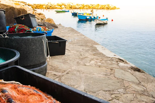 地中海渔村码头 有鼓和容器 有停泊的船在背景下满渔网 — 图库照片
