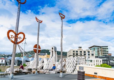 Wellington, Yeni Zelanda - 1 Ekim 2018; Ahşap Heykel Paratene Matchitt tarafından 1993 yılında yaya köprüsü waterfront için Civic kare bağlama City yüklü deniz şehre arasında iki kişi oturmak