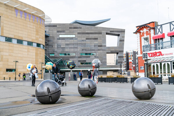 WELLINGTON, NEW ZEALAND - OCTOBER 1 2018; Tourists and three  Other Worlds sculpture by Ruth Watson installed in 2018  and grey light balls by Chris Gregory on Wellington waterfront with architectural features of Te Papa, New Zealand Museum behind.