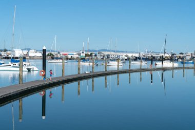 Mavi sakin su kırmızı can yeleği ayakta balık Tauranga Yeni Zelanda gün ışığında küçük çocuk ile çevrili uzun kıvrımlı pier.