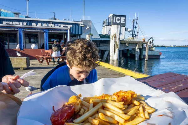 2018年12月20日 新西兰 陶兰加 在鱼市场外身穿蓝色球衣 头戴鱼尾纹和碎屑的小男孩在吃饭前都会看上一眼 — 图库照片