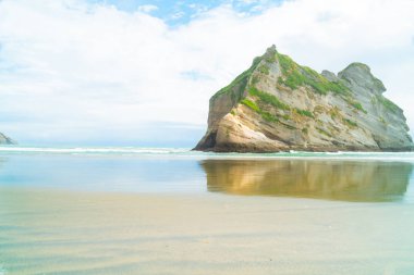Erozyon - shore relected Wharaiki Beach yakınındaki Farewell Spit South Island Yeni Zelanda sakin suda yaşları sonra büyük rock yaptı