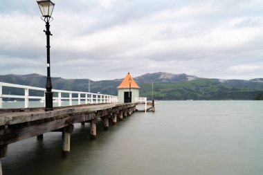 Daly's Wharf veya Akaroa döken ve turuncu ile Akaroa Limanı İskele yuvarlak sonunda konik çatı