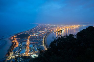 Kentsel gece ışıkları Simgesel Yapı Mount Maunganui okyanus plaj bir tarafında ve liman ile aşağıda popüler touriist hedef şehir üstünden .