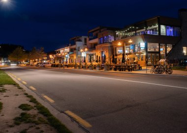 Wanaka Yeni Zelanda - 16 Ekim 2018; Kafe ve barlar gece karanlıkta parlayan küçük turistik şehir sokakları satır.