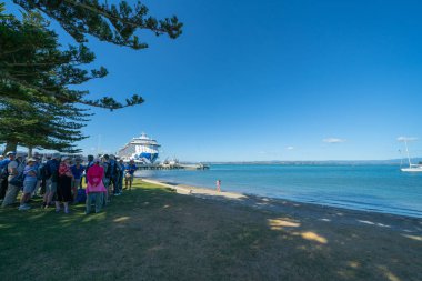 Mount Maunganui Yeni Zelanda - 10 Şubat 2019: Cruise gemisi yolcu tribünde Piulot tur rehberi için dinleme körfeze üzerinde gölge grup