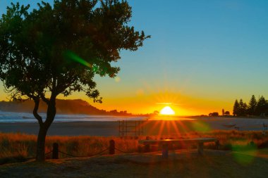 Mount Maunganui arka ışıklar manzara ana plaj, Tauranga Yeni Zelanda yoğun güneş doğarken.
