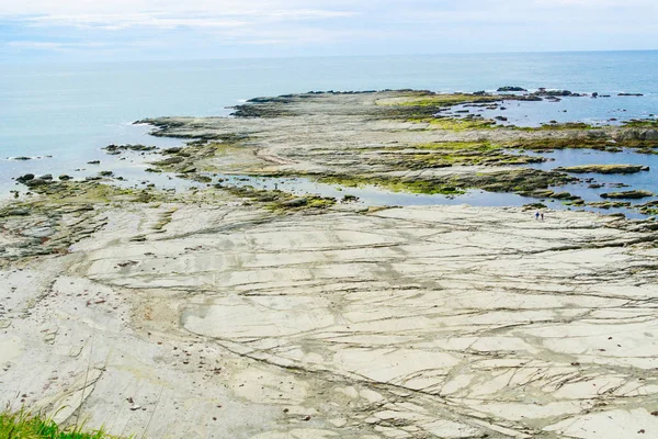 Bred platt lera-klippavsats sträcker sig ut i havet — Stockfoto