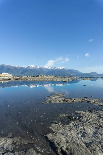Snow-capped Kaikoura Mountains reflected in calm rockpool — Stock Photo, Image