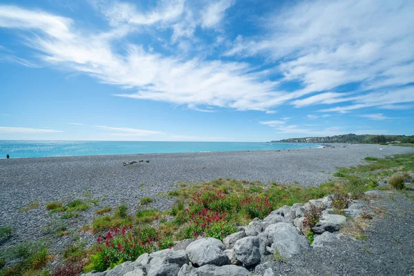 Praia de Kaikoura pedregosa e mar sob céu azul com nuvens brancas — Fotografia de Stock