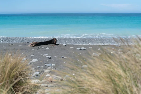 Каменистый пляж с морем и голубым небом за его пределами в качестве живописного фона — стоковое фото
