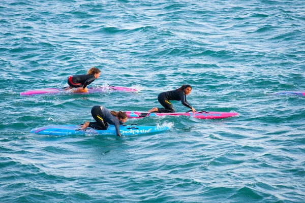 Turkuaz deniz üzerinde parlak kürek tahtasında üç genç kadın. — Stok fotoğraf