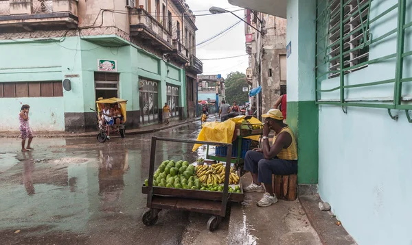 Ο άνθρωπος με καλάθι φρούτων κάθεται καταφύγιο από βαριά βροχή ελπίζοντας να se — Φωτογραφία Αρχείου