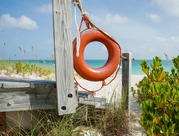 Luminosa vita arancione bouy appeso sul lato di accesso alla spiaggia su tropi — Foto Stock