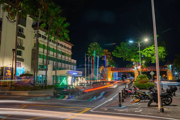 Escena callejera con luces de neón y senderos de luz de coches en movimiento — Foto de Stock