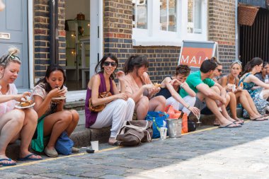  kaldırım boyunca oturan grup genç yetişkinler