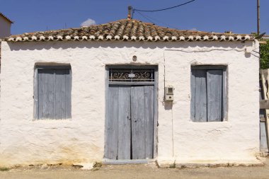 Kapalı, kapısı ve iki penceresi olan basit bir ev.