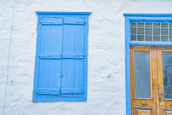 Edifício branqueado com porta azul e obturador — Fotografia de Stock