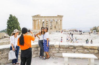 Akropolis 'te Parthenon' un önünde fotoğraf çeken turistler.