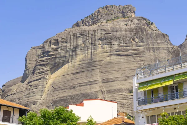 Une énorme formation rocheuse s'élève au-dessus des maisons de Meteora — Photo