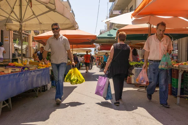 Las personas con sus compras caminan entre vendedores de productos de mercado —  Fotos de Stock