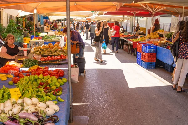 Menschen mit ihren Einkäufen laufen zwischen den Marktbeschickern umher — Stockfoto