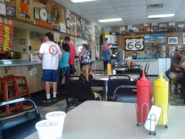 Springfield Illinois ABD - 31 Ağustos 2015; 66. Yol boyunca küçük bir kasaba kafeteryasındaki insanlar, tüm yol tabelaları ve koleksiyonları, klasik plastik hardal ve ketçap şişeleriyle kafe masası.