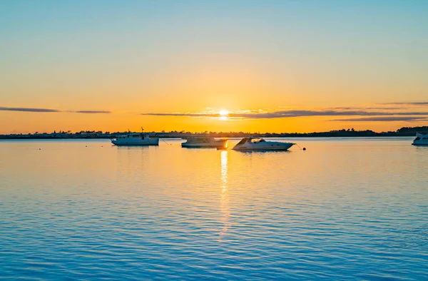 三艘船在日出时分停泊在陶兰加港蓝色水面上的地平线附近 地平线上闪烁着强烈的金色阳光 — 图库照片