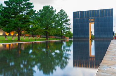 Oklahoma City USA - 9 Eylül 2015; Oklahoma National Memorial Gate of Time and Reflecting Pool with Field of Empty sandalye under trees on left.