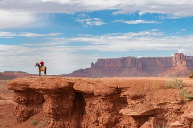 Utah ABD - 23 Eylül 2015; Utah ABD 'de jeolojik kaya çıkıntılarının jeolojik kaya yapıları arasında kırmızı kaya çıkıntısı üzerinde at sırtında Kovboy