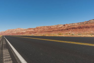 Arizona 'nın çöl ve kırmızı kayalık bölgelerinde ilerleyen bir yol ve kayalıklarla kaplı bir otoban..