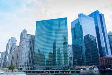 Nehrin üzerinde yükselen Chicago ticari gökdelenleri ve diğer taraftaki binaları yansıtan cam perdeler..