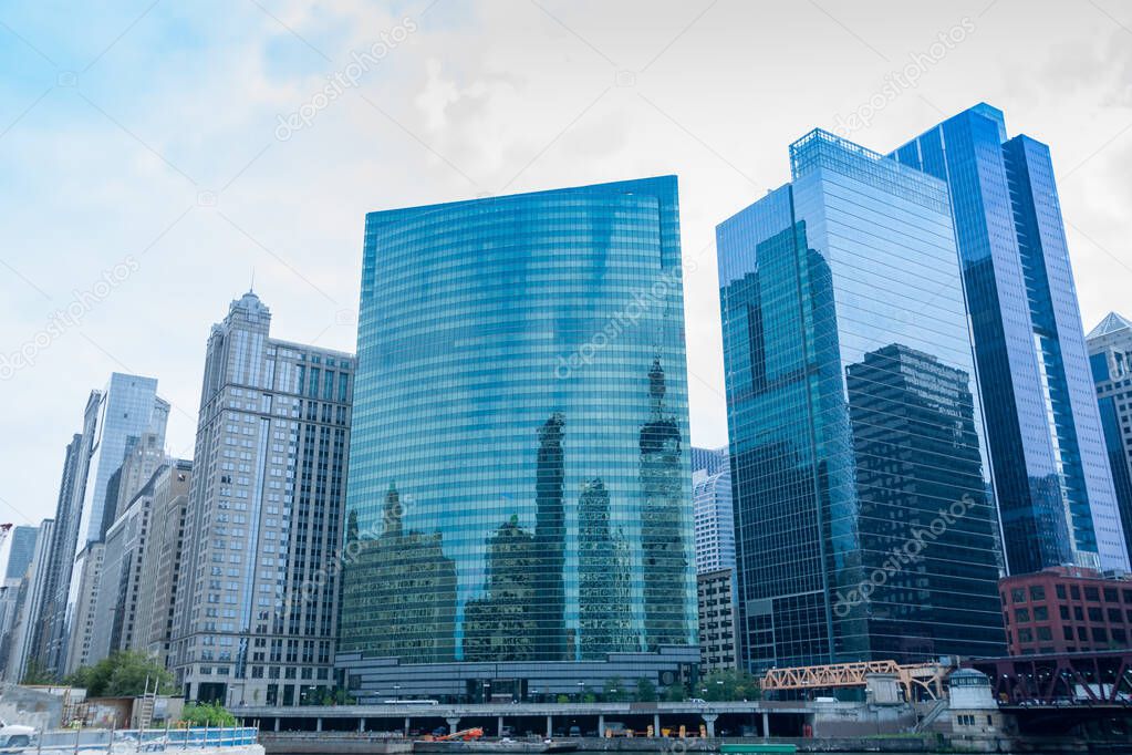 Chicago commercial high-rise skyline rising above river with glass curtain exteriors reflecting buildings on otherside.