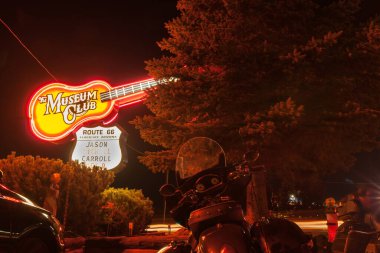 Flagstaff Arizona - 26 Eylül 2015; Müze Kulübü 'nün dev neon ışıklı tabelası karanlık gecede aşağıda motosikletler park halinde. Arizona Route 66, ABD.