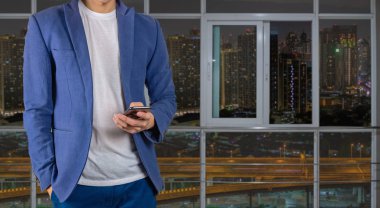 Şehir Manzaralı pencerenin önünde telefonu kullanan adam