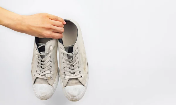 White dirty sneaker shoes with hand holding on white background