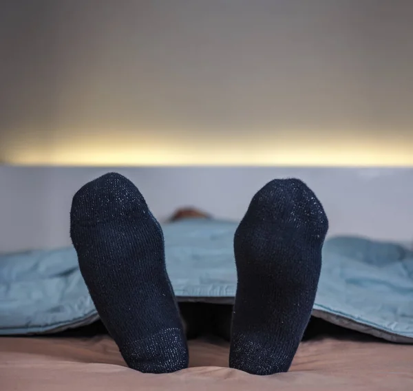 Feet wearing sock on bed