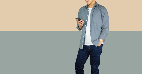 Mann mit Smartphone in lässigem Tuch auf braunem und grauem Hintergrund — Stockfoto