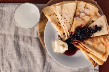 Bir havlu zemin üzerine sütle kahvaltıda krep. Krep reçel ve tereyağı ile.