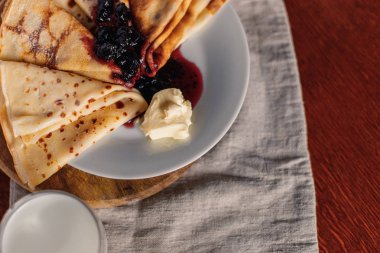 Bir havlu zemin üzerine sütle kahvaltıda krep. Krep reçel ve tereyağı ile. Üstten görünüm. Görünümü Kapat